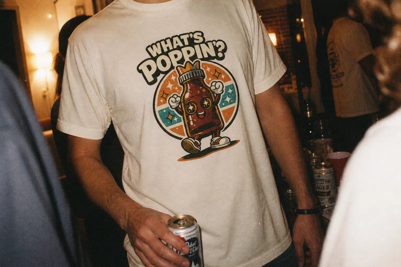 What’s Poppin’ graphic tee with retro bottle character on ivory shirt, queer nightlife inspired design